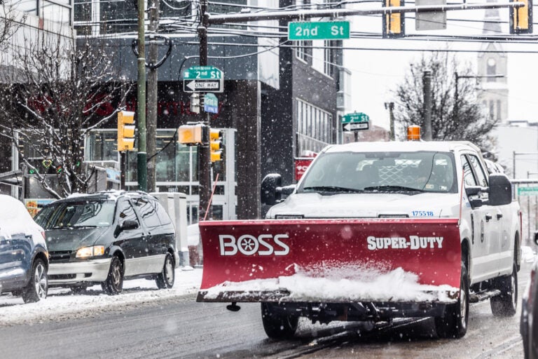 A city plow truck driving a snowy street