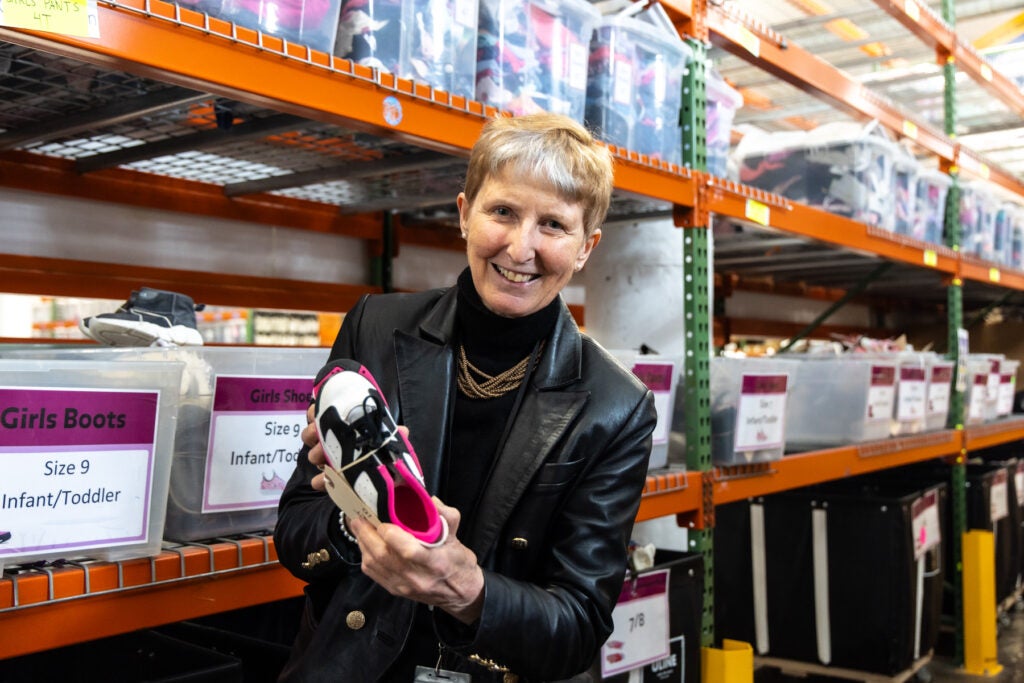 Michal Smith smiles while holding a shoe
