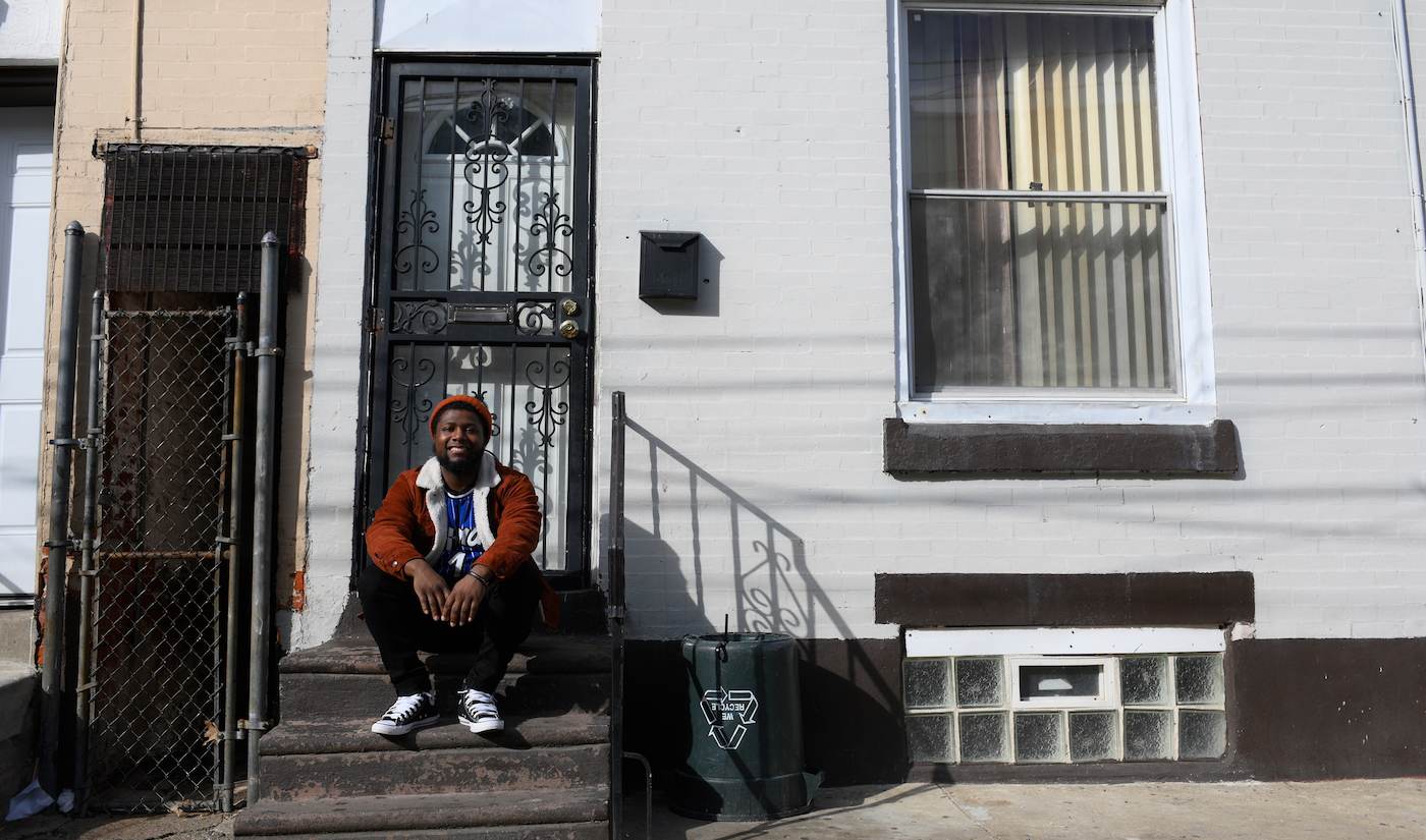 Shakoor sits in front of his father’s childhood home. He sees opportunity on the same Philly streets that nearly destroyed his parents. “I’m out of the chaos.” (Bastiaan Slabbers for WHYY)