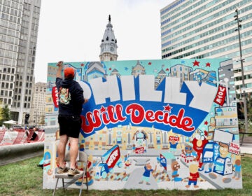 Man details a mural that reads 
