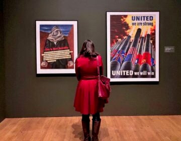 A visitors look at two posters, one reading UNITED we are strong UNITED we will win and This is Nazi brutality