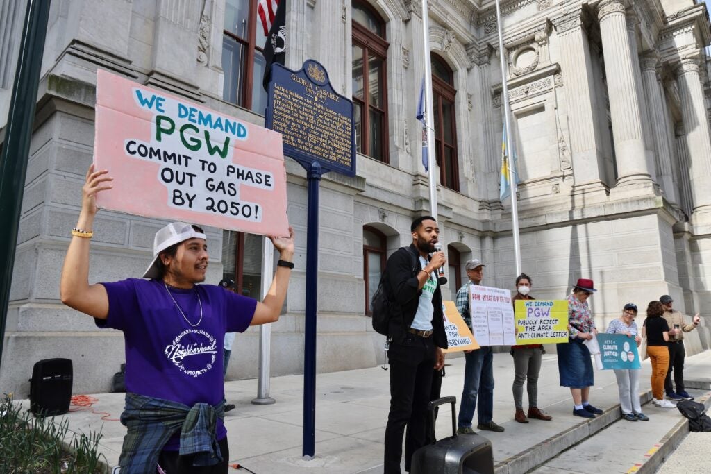 Activists rallying, one holding a sign reading WE DEMAND PGW COMMIT TO PHASE OUT GAS BY 2050!