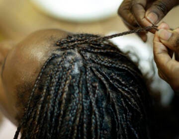 Shelly Smith braids hair for Bridget Dunmore at her salon, Braid Heaven Tuesday, Jan. 28, 2020 in Kansas City, Kan. (AP Photo/Charlie Riedel)