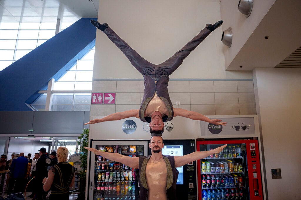 A man balances upside on top of his head while on top of another man's head
