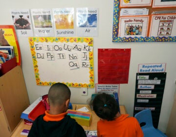 Two students help put away supplies in a classroom