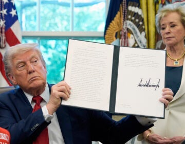 President Donald Trump holds up a signed executive order with education secretary Linda McMahon behind him