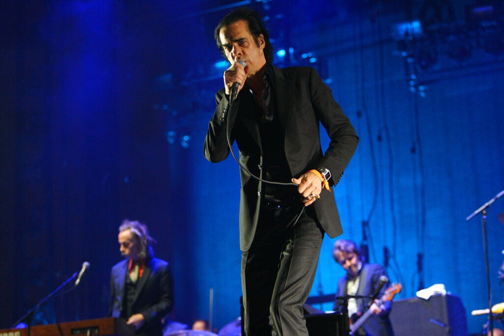 Nick Cave and the Bad Seeds perform music on stage