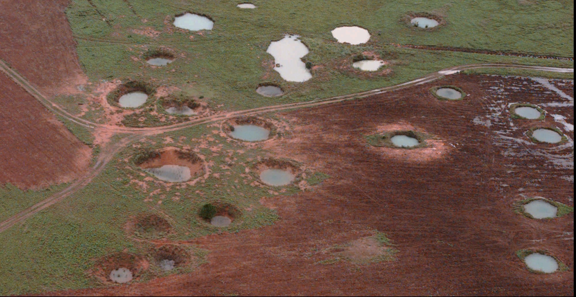 What appears to be ponds are actually water-filled bomb craters from the Vietnam War era, as seen from a helicopter, May 25, 1997, near the northeastern Laotian village of Sam Neau.(AP Photo/David Longstreath)