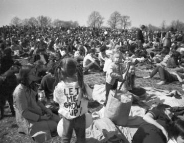 A black-and-white photo shows people gathered in a park.