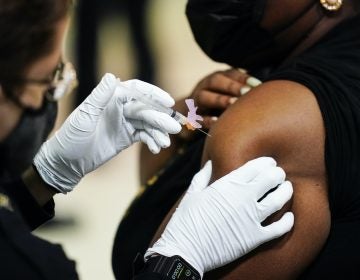 A member of the Philadelphia Fire Department administers the Johnson & Johnson COVID-19 vaccine to a person at a vaccination site setup