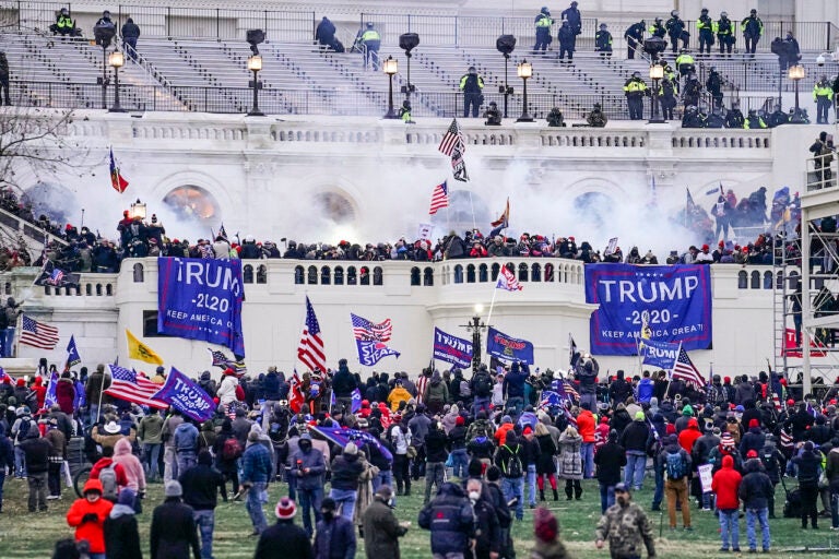 Protesters holding Trump 2020 flags and signs storm the Capitol in Washington D.C.