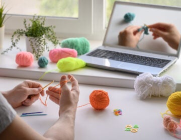 A man is crocheting and watching a tutorial video. (Ramil Gibadullin/Bigstock)