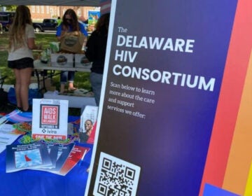 a poster reads DELAWARE HIV CONSORTIUM under a tent at an event