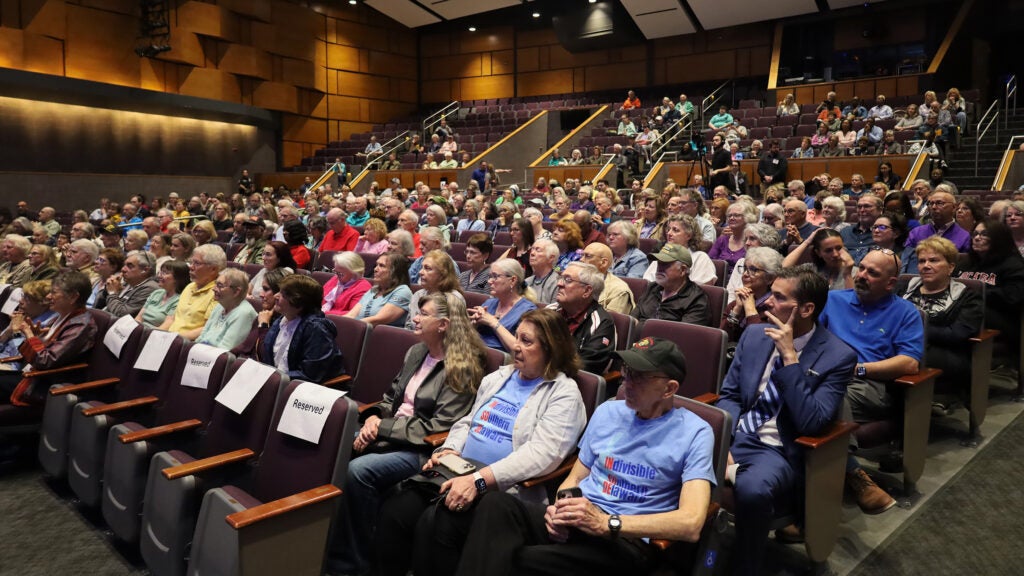 A large group of people sitting in the audience watching the town hall