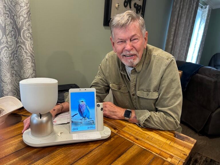 Anthony Niemiec with ElliQ, an AI companion robot, in Beacon, New York. (Dawn Attride/For WHYY)