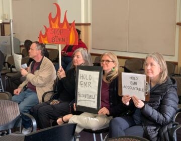 Camden residents hold signs reading STOP the BURN and HOLD EMR ACCOUNTABLE