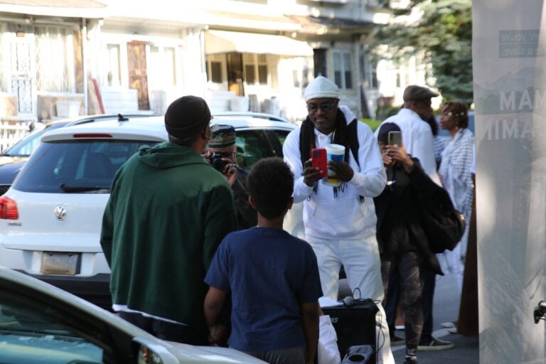 Philadelphians and loved ones of the Africa family on the sidewalk of Cobbs Creek Parkway