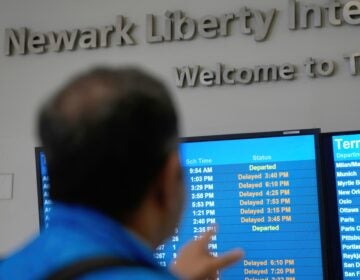 A display shows the status of flights at Newark Liberty International Airport