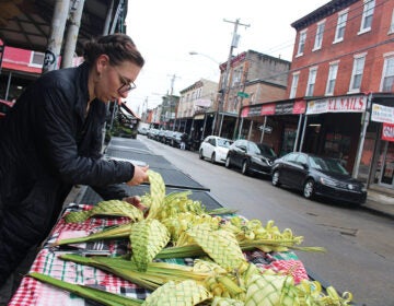 A woman weaves designs with palm fronds in Philadelphia's Italian market.