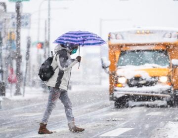 A person crosses a street during a winter snow storm in Philadelphia, Tuesday, Feb. 13, 2024.