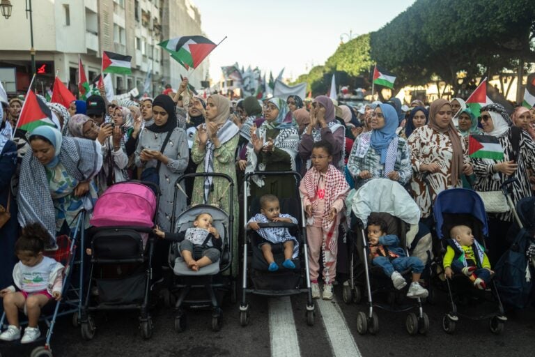 Moroccan women wave flags alongside their children