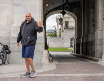 U.S. Sen. John Fetterman waves to the media while wearing gym shorts and a sweatshort