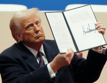 President Donald Trump holding up executive order
