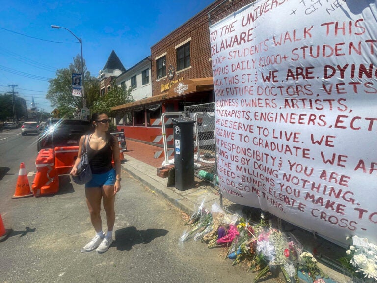 Crystal Sandoval stands by a memorial for the car crash at the University of Delaware