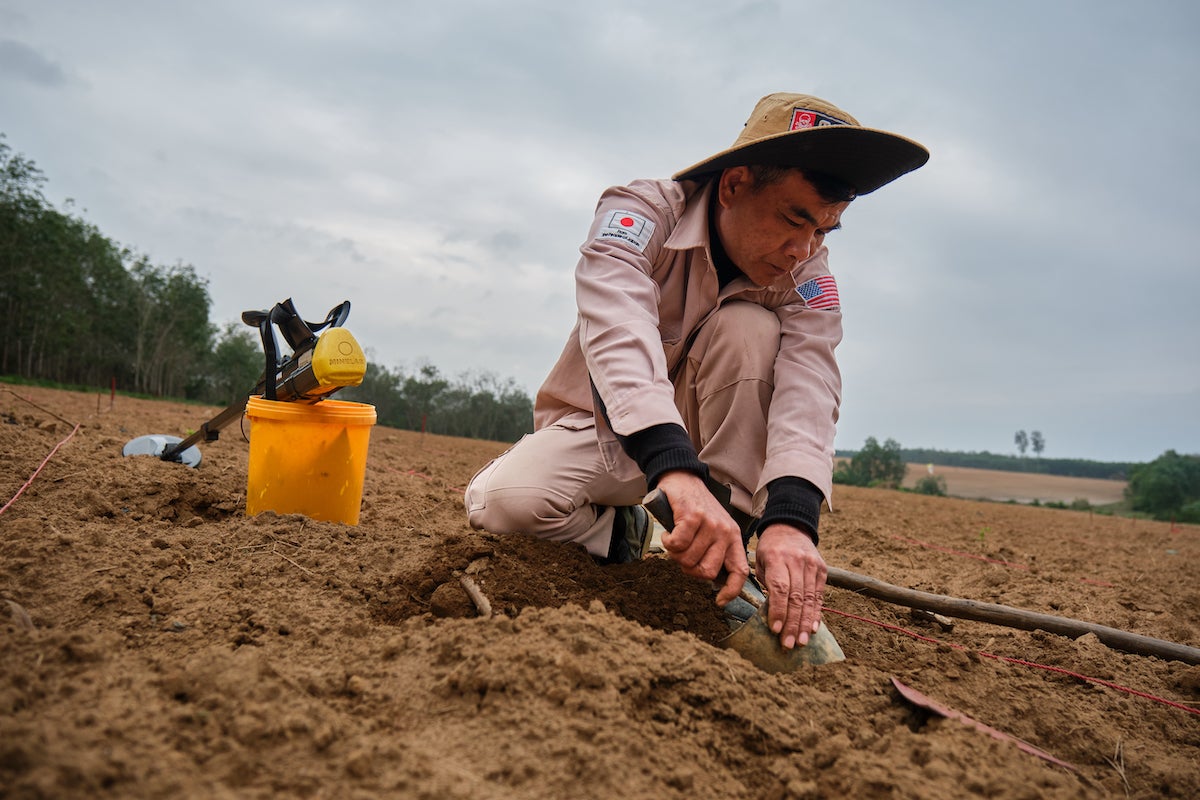 A worker from the Mines Advisory Group is carefully extracting an unexploded ordinance from the ground. (Mines Advisory Group/Bart Verweij)