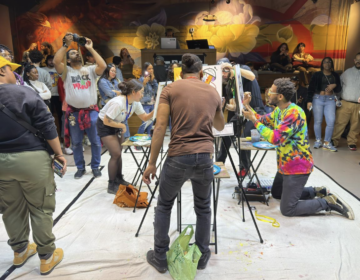 2 artists painting facing each other , with a crowd circled around them